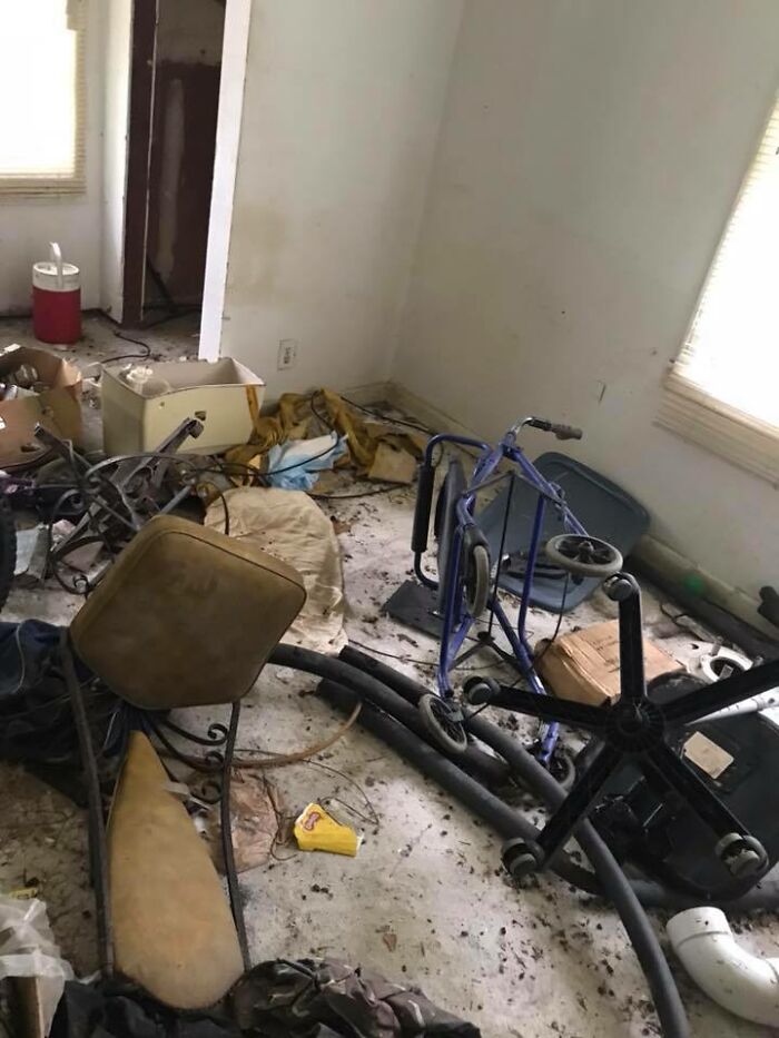 Cluttered and dirty room with broken furniture, discarded items, and debris, one of the worst real estate photos ever.