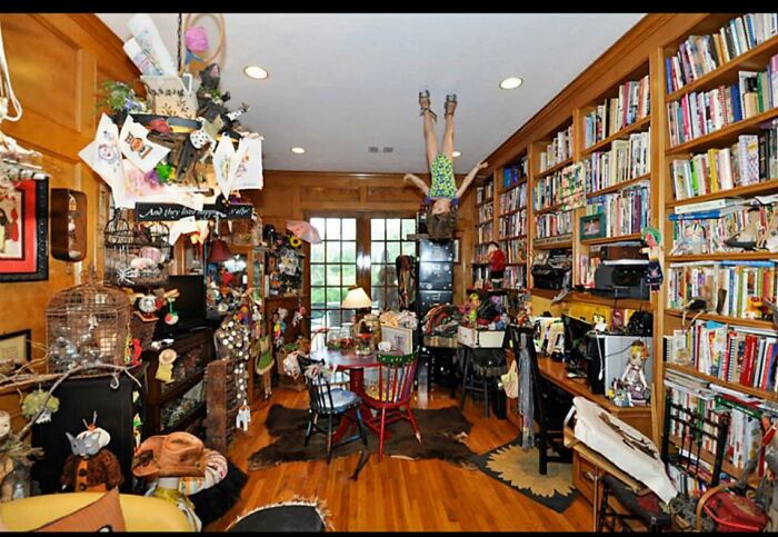 Cluttered room with numerous decorations, bookshelves, and an upside-down mannequin creating a worst real estate photos ever look.