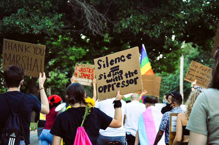 Protesters holding signs advocating against misogyny and gender-based violence in an outdoor demonstration.