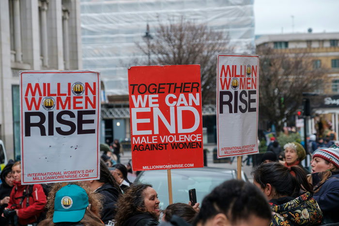 Protesters holding signs against misogyny and male violence at a gender-based violence awareness rally outdoors.