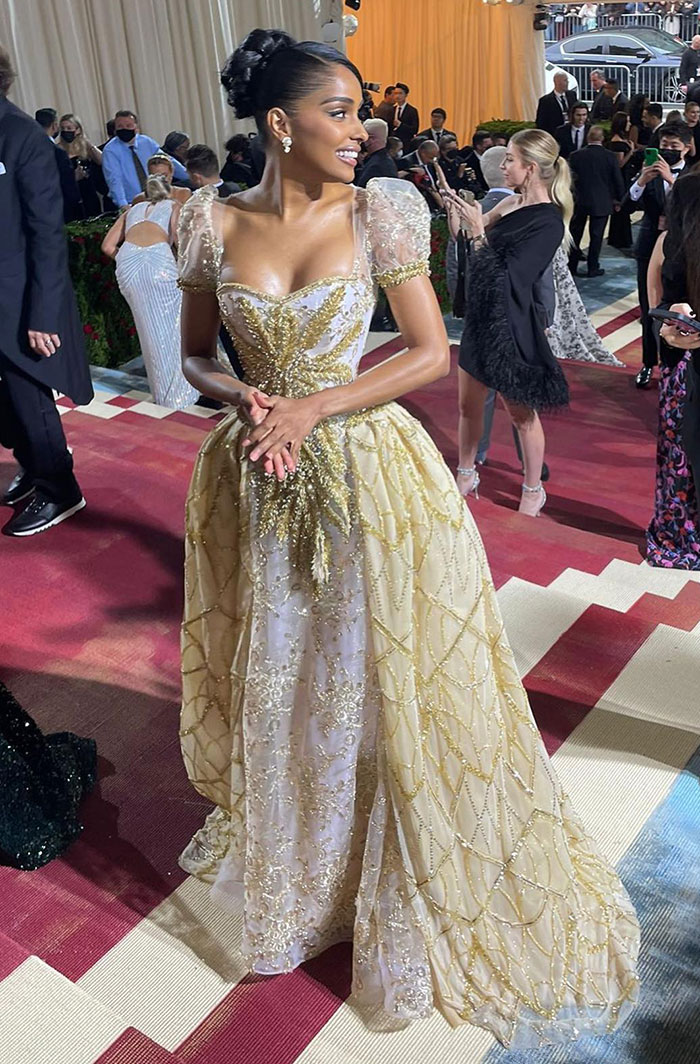 Reporter outshines celebs on Met Gala red carpet, wearing an elegant gold and white embellished gown with puff sleeves. Reporter outshines celebs on Met Gala red carpet, wearing an elegant gold and white embellished gown with puff sleeves.