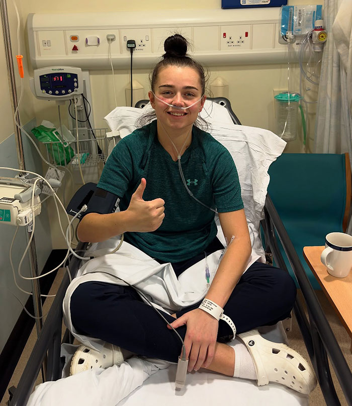 Young woman hospitalized with oxygen tube and medical monitoring equipment giving thumbs up in hospital bed. Young woman hospitalized with oxygen tube and medical monitoring equipment giving thumbs up in hospital bed.