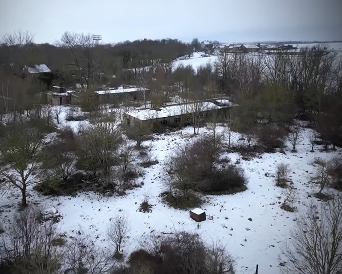 Snow-covered abandoned buildings surrounded by trees in a winter landscape linked to Madeleine McCann investigation.