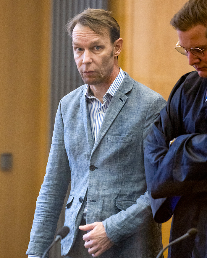 Man in a gray blazer speaking indoors with German police in background after evidence Madeleine McCann is deceased news.