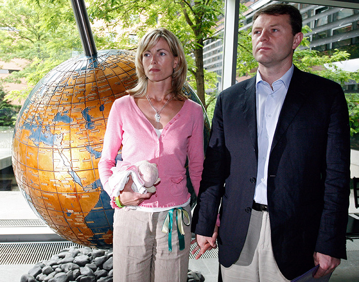 Couple standing near large globe indoors, woman holding a doll, related to Madeleine McCann German police urgent request.