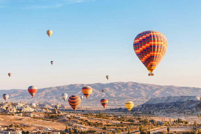 Colorful hot air balloons floating over a mountainous landscape, showcasing one of the wonders proving the world is still magical.