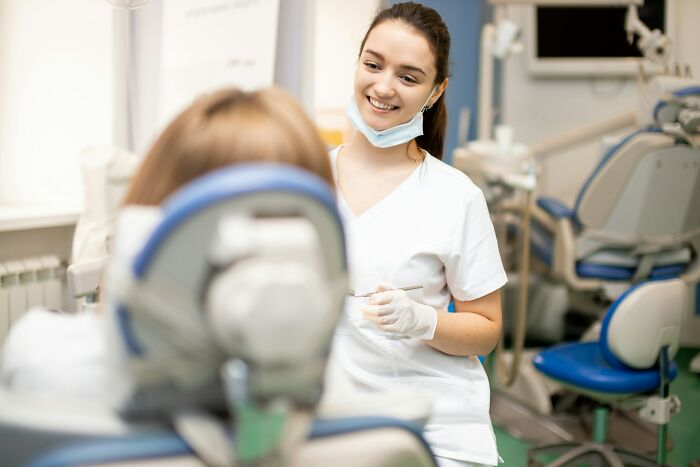 Dentist smiling and examining patient in clinic, highlighting moments people were served really good or bad genes.
