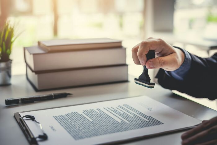 Person stamping a confidential document at a desk, illustrating company secret being revealed after employment.