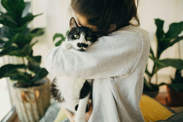 Woman hugging a black and white cat indoors, showing a small decision that changed her life unexpectedly.