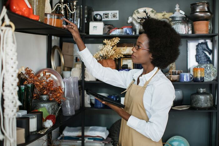 Woman in apron organizing items on shelves inside store, illustrating industry secrets behind closed doors.
