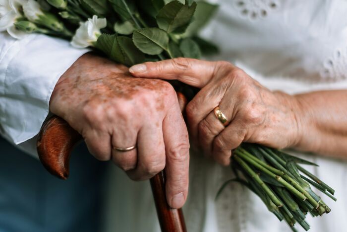 Close-up of elderly hands holding a bouquet and a cane, symbolizing a small decision that changed life forever.