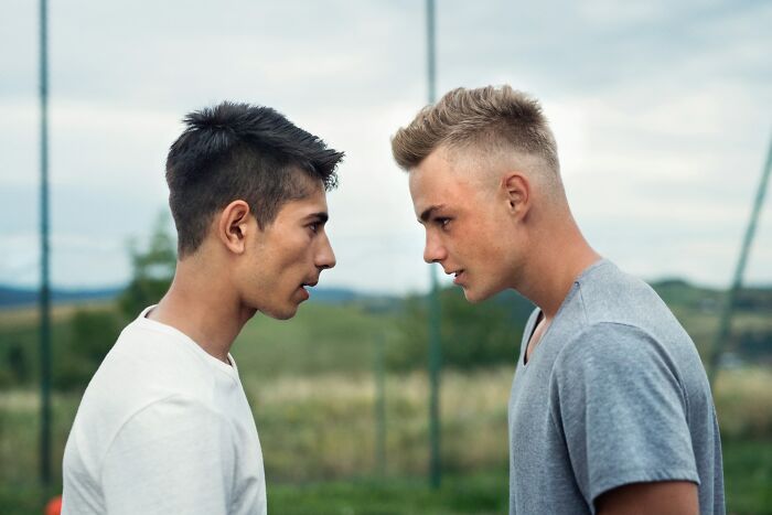 Two young men facing each other outdoors, engaged in a serious conversation about questions women would ask men.