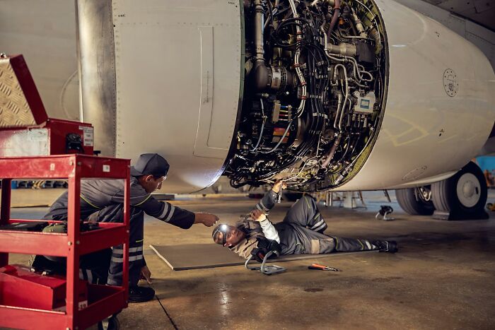 Two mechanics inspecting and repairing an aircraft engine, revealing industry secrets behind closed doors.
