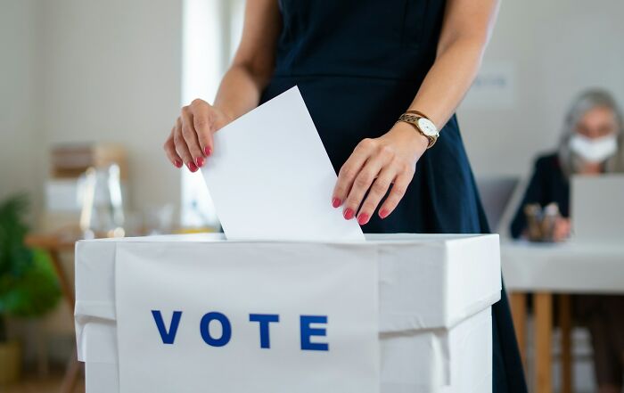 Person placing a ballot in a box labeled vote, illustrating the concept of company secret sharing after employment ends.