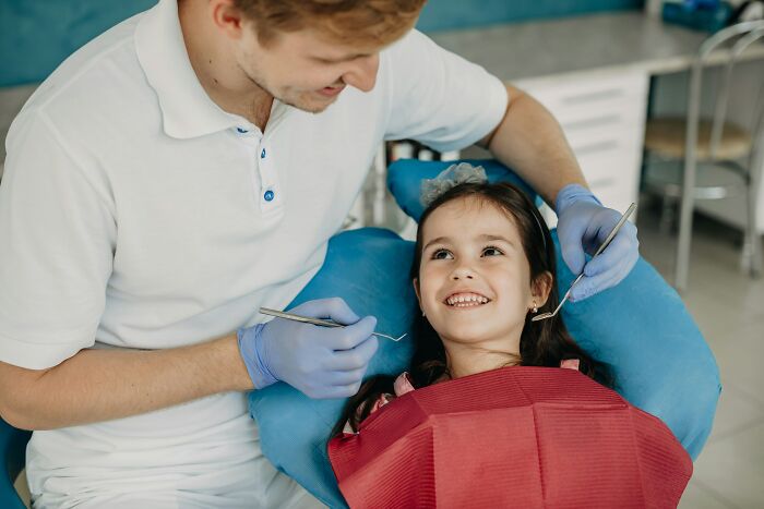 Dentist with gloves treating a young girl in a dental chair, highlighting hilariously bad names that make people question parents.