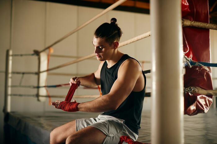 Young man in a boxing ring wrapping his hands, symbolizing the wildest life blunders people keep secret.