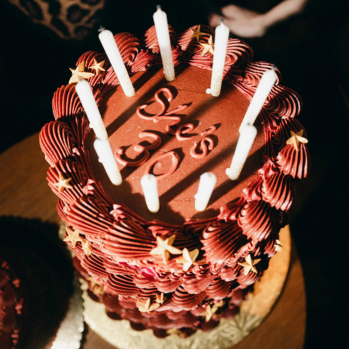 Red layered cake with white candles celebrating Gigi Hadid and Bradley Cooper relationship and age gap discussion. Red layered cake with white candles celebrating Gigi Hadid and Bradley Cooper relationship and age gap discussion.