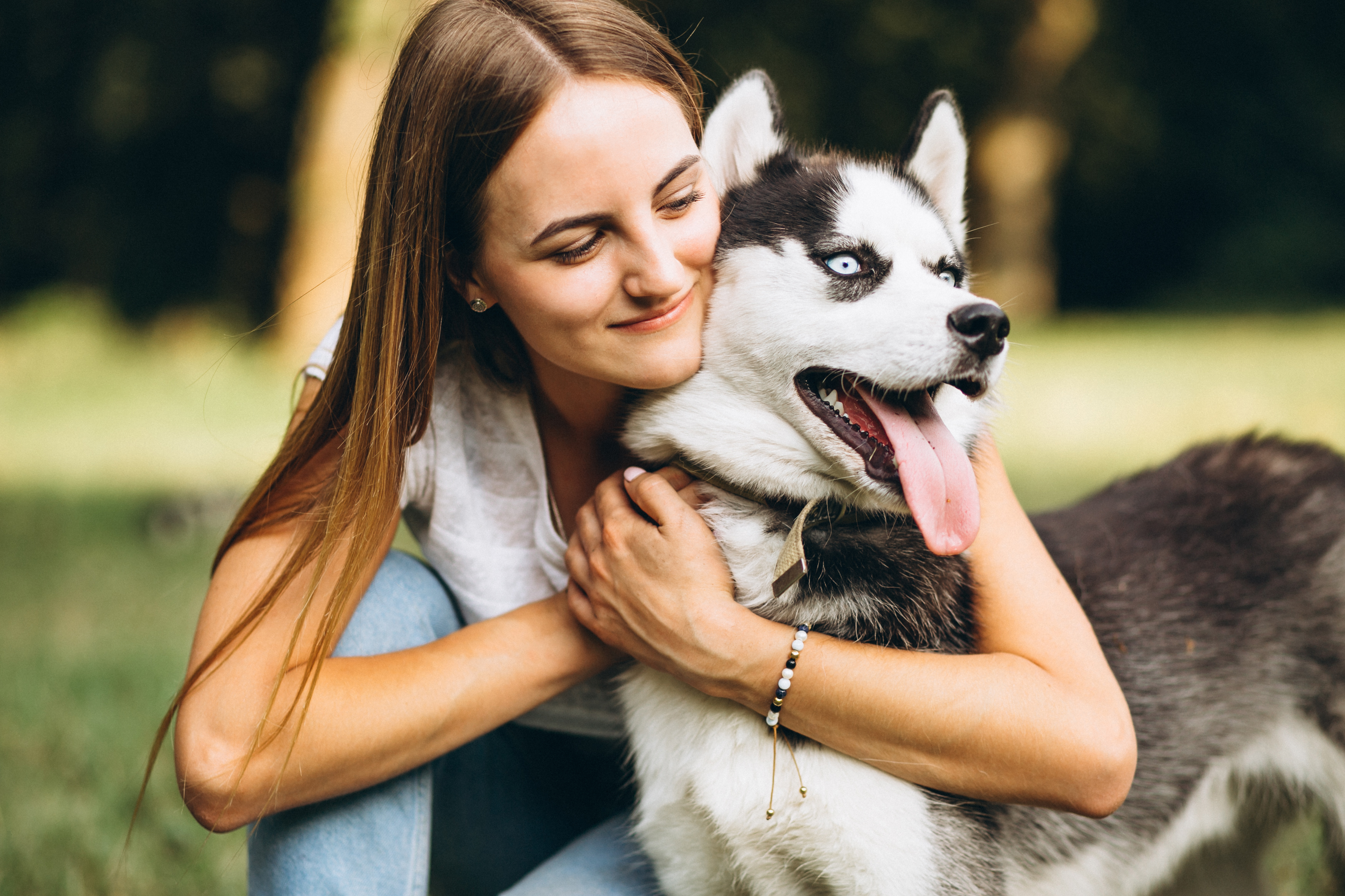 Young woman hugging a happy husky dog outdoors, illustrating the heartbreaking cancer diagnosis involving husband's condition.