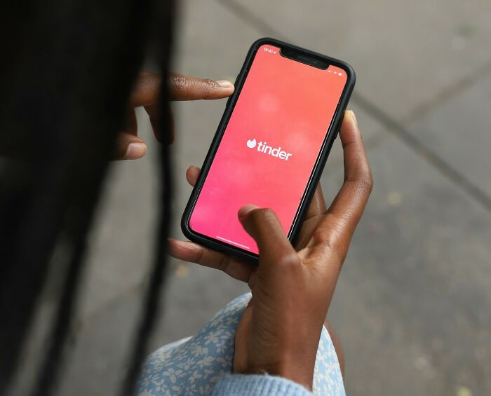 Person holding a phone with Tinder app open, illustrating shocking experiences people have lived through.
