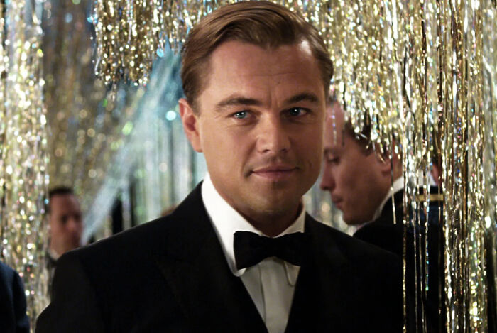 A well-dressed man at a party with gold streamers, representing literature geniuses in a general knowledge quiz setting. A well-dressed man at a party with gold streamers, representing literature geniuses in a general knowledge quiz setting.