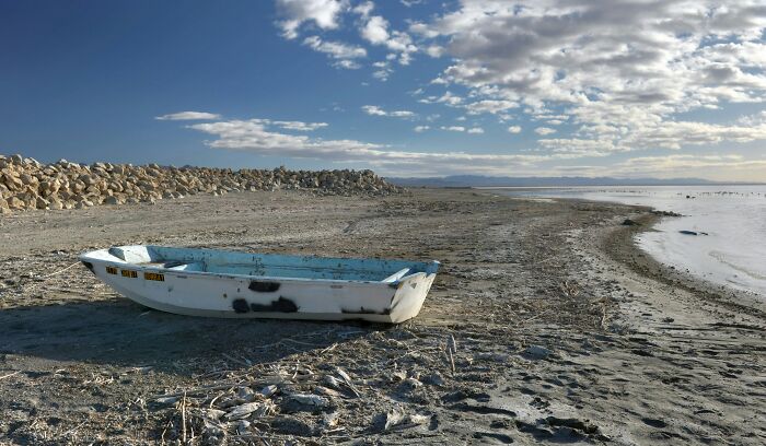 Abandoned boat on a deserted shore at a faded tourist destination, showcasing lost popularity and neglect.