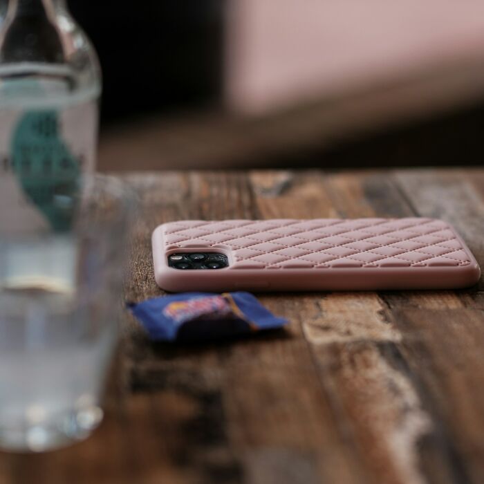 Smartphone with a textured case on a wooden surface, highlighting improvements related to quality of life essentials.