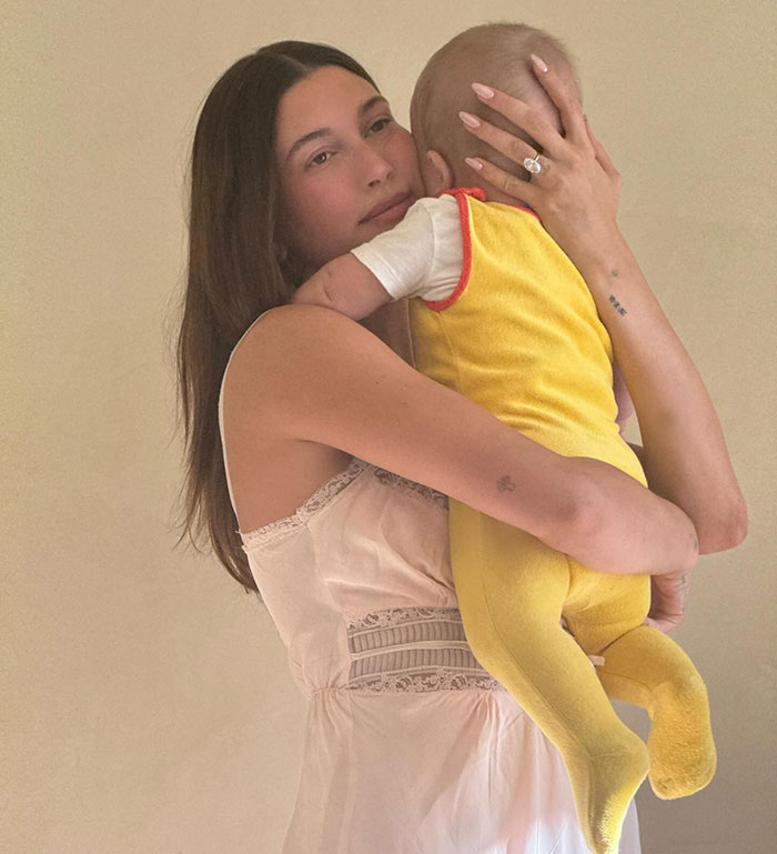 Woman in light dress holding a baby in yellow outfit, highlighting themes of disrespect and love language in media coverage.