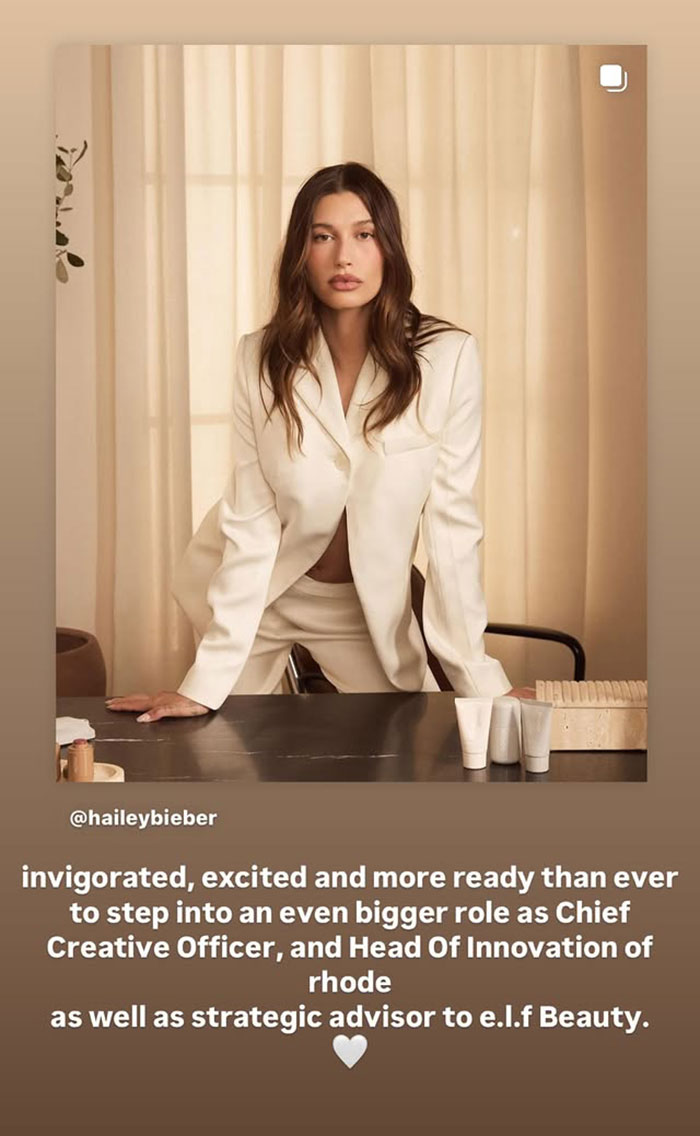 Hailey Bieber in a cream suit posing confidently at a desk, related to Justin Bieber grabbing wife Hailey&rsquo;s breasts news.