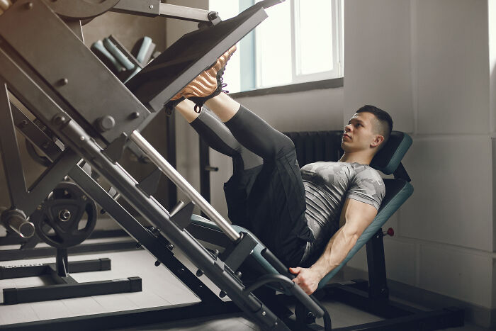 Man working out on leg press machine in gym, illustrating weirdest ways people earned quick money.
