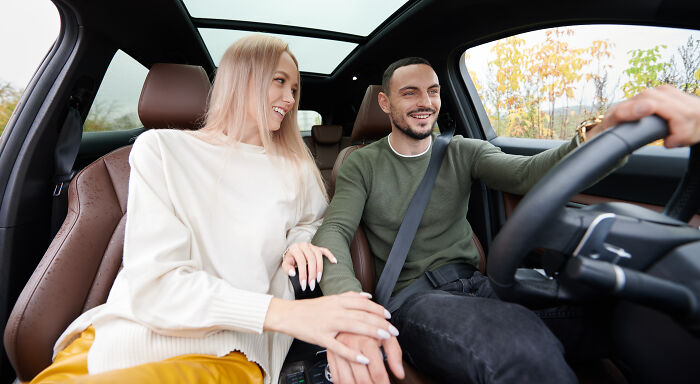 A couple smiling and holding hands inside a car, showcasing a small decision that changed life unexpectedly.