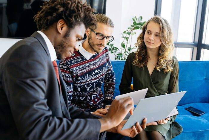 Three young professionals discussing childhood habits and red flags using a tablet in a modern office setting.