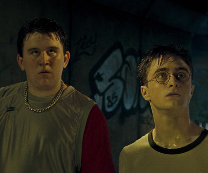 Two young men in a dark urban setting, featuring a Harry Potter star in a scene from an X-rated gay film.