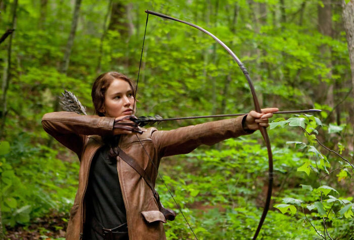 Young woman practicing archery in a forest, illustrating unconventional crushes people actually have.