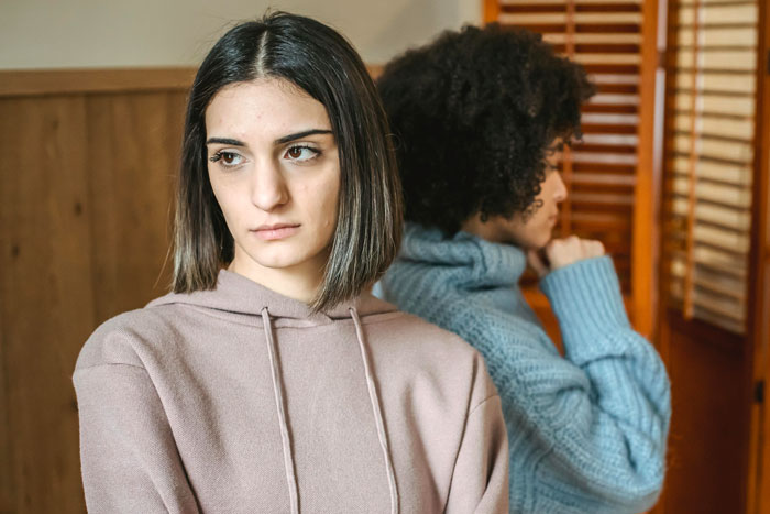 Two women turned away from each other, showing tension and refusal to help with debts between sisters. Two women turned away from each other, showing tension and refusal to help with debts between sisters.