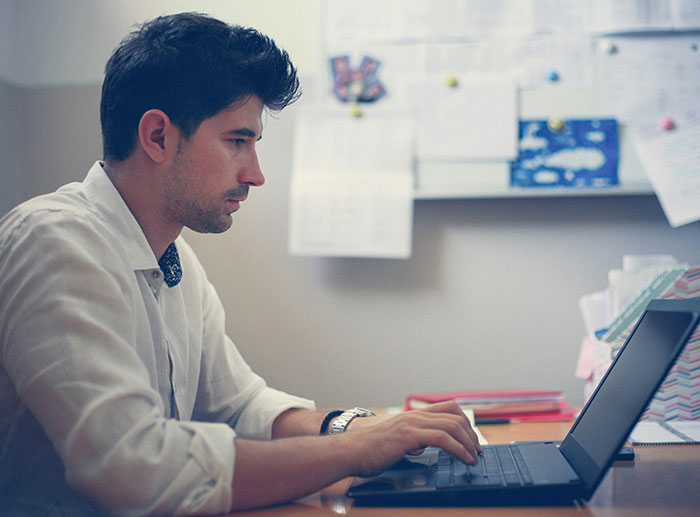 Employee working on laptop at desk, focused and determined, illustrating how to only work a week a month concept. Employee working on laptop at desk, focused and determined, illustrating how to only work a week a month concept.