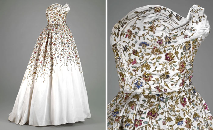 Vintage white gown with intricate floral embroidery, showcasing centuries of fashion in detailed craftsmanship and design.