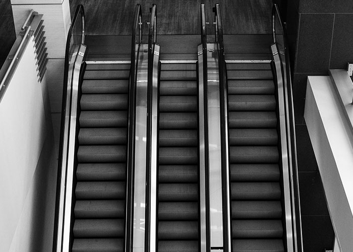 Black and white photo of empty escalators in a modern building, symbolizing things from the past people keep researching.