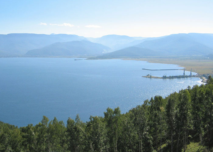 Scenic lake with surrounding forest and mountains, representing things that happened in the past people research continuously.