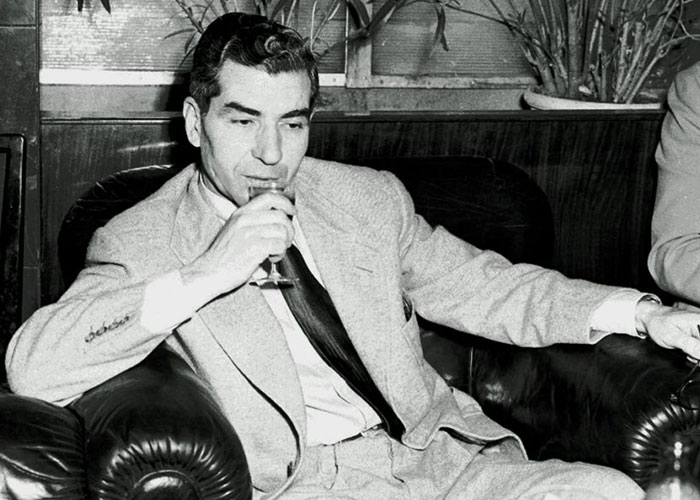 Black and white photo of a man in a suit sipping a drink, representing things that happened in the past people research.