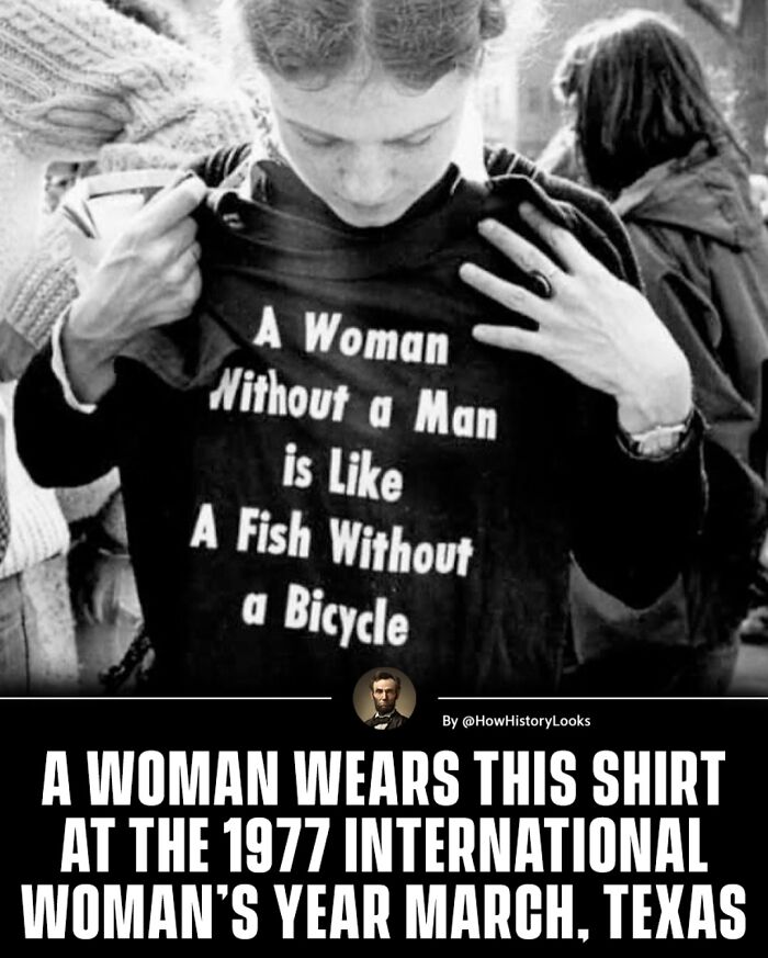 Woman at 1977 International Women’s Year March in Texas wearing a shirt with a feminist slogan about independence and history.