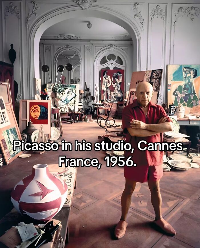 Picasso in his studio surrounded by art, capturing monumental life moments frozen in time in 1956 Cannes, France.