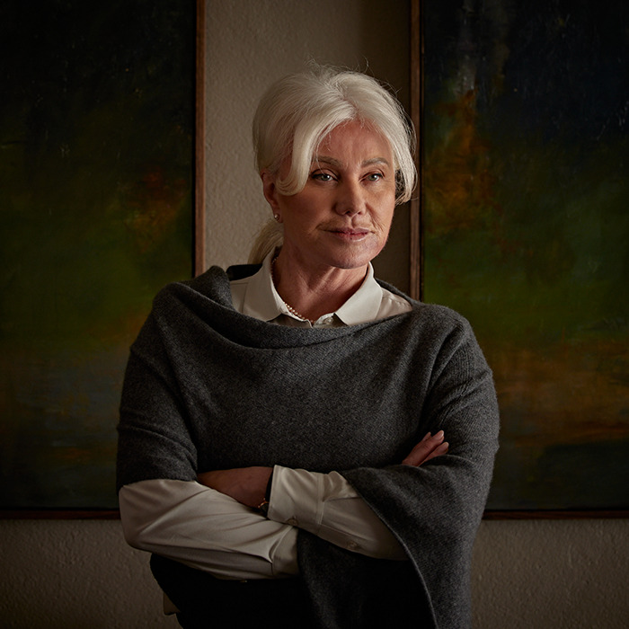 Mature woman with white hair wearing a gray shawl and white blouse, looking thoughtful in a dimly lit room. Mature woman with white hair wearing a gray shawl and white blouse, looking thoughtful in a dimly lit room.