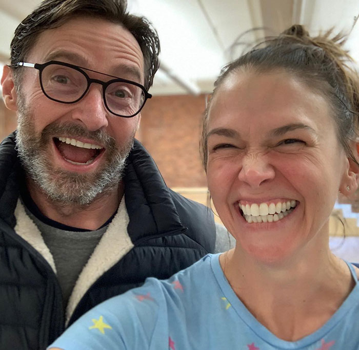 Hugh Jackman and Sutton Foster smiling brightly together in a casual indoor setting, highlighting their history.