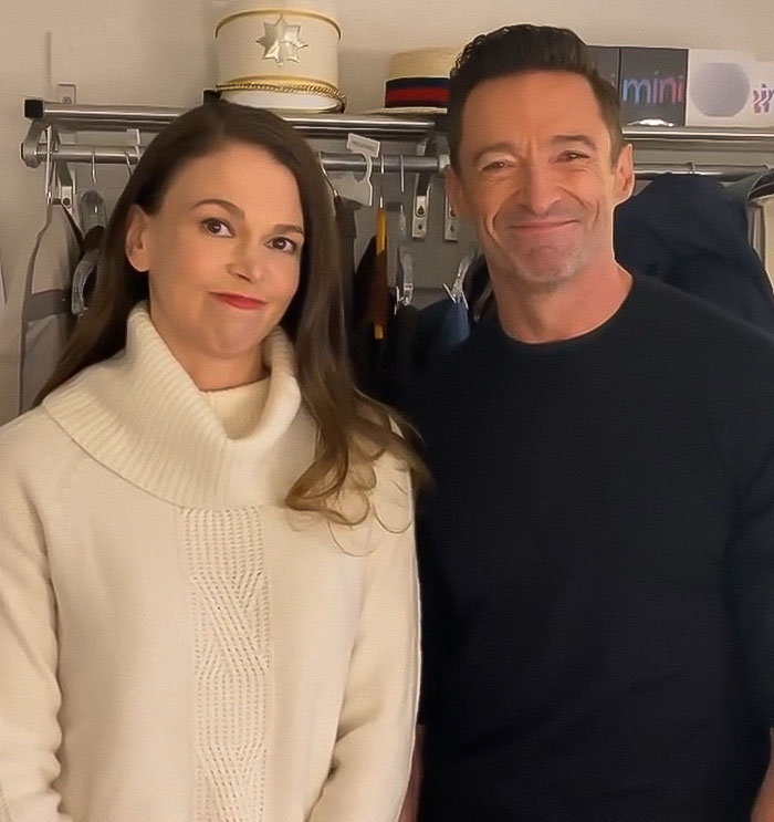 Hugh Jackman and Sutton Foster standing together indoors, smiling, highlighting their long history connection.