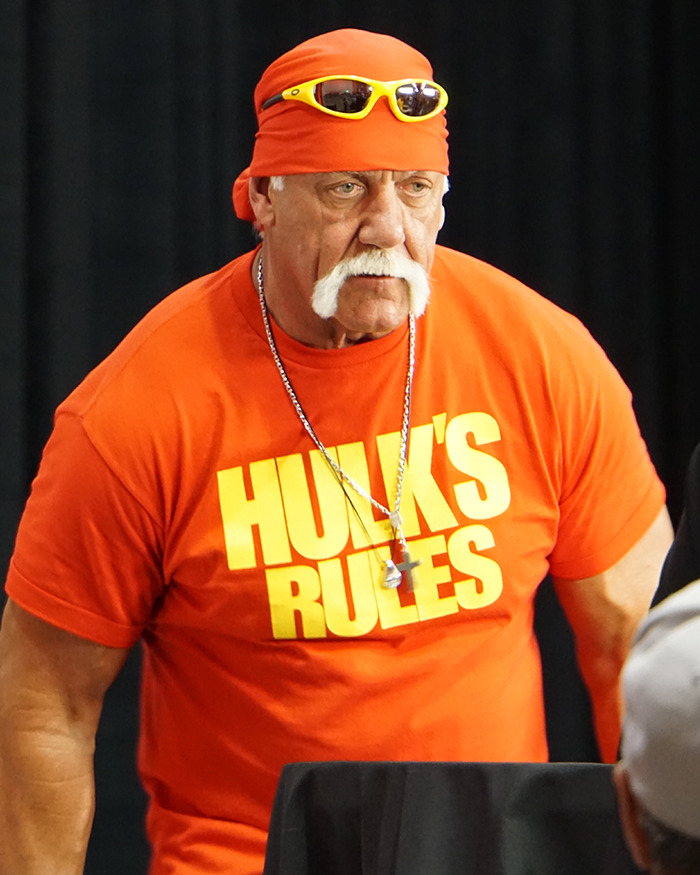 Hulk Hogan in a bright orange shirt and bandana, showing his eyes and new look at 71 during a public appearance.