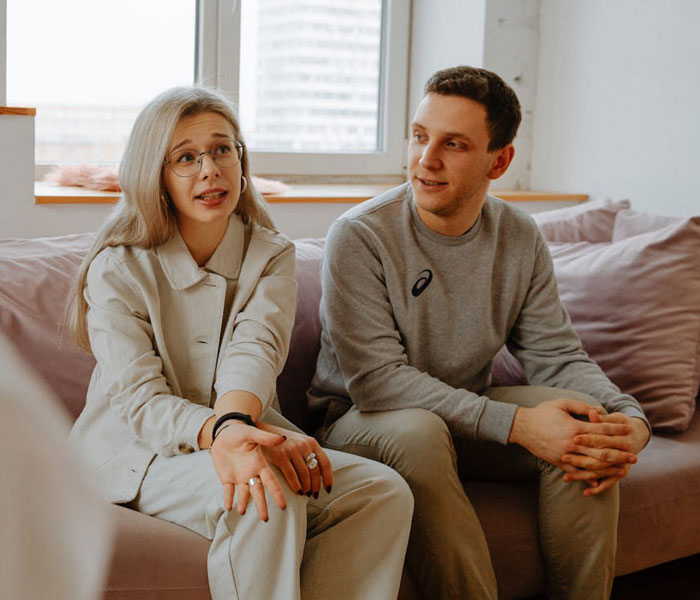 Woman and man sitting on couch in tense conversation about paternity test and marriage issues after 24 years together. Woman and man sitting on couch in tense conversation about paternity test and marriage issues after 24 years together.