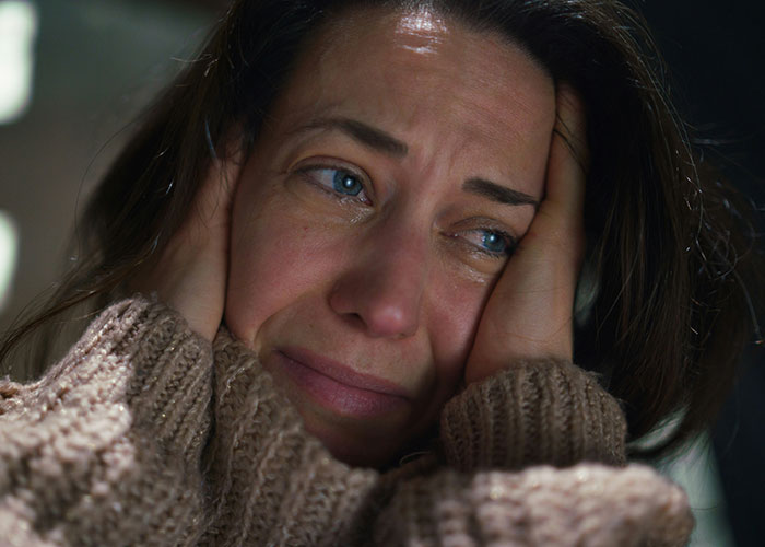 Close-up of a woman in a cozy sweater looking tearful and distressed, reflecting emotional pain after a difficult date.
