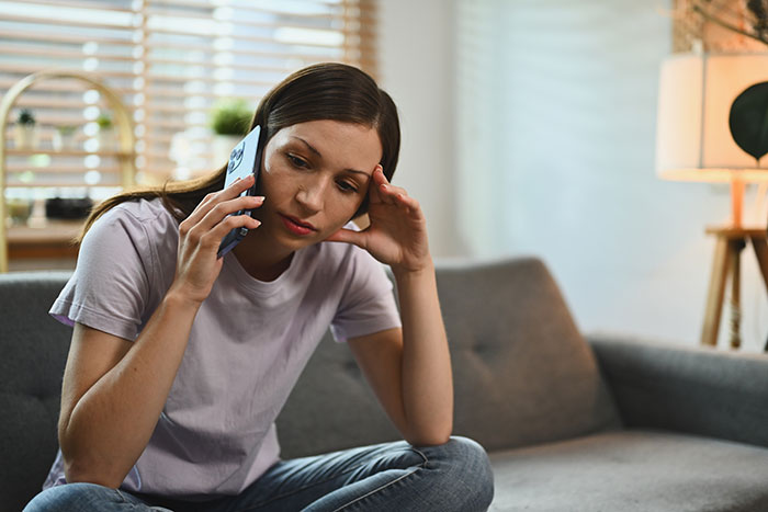 Woman looking concerned while talking on the phone, reflecting on husband jealousy at their wedding over the girl he led on.