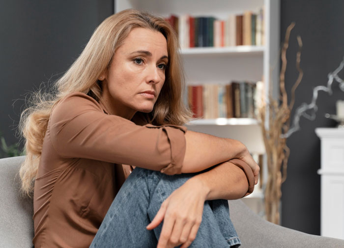Woman looking upset and reflective after husband undermines wife&rsquo;s job in front of his boss, causing tension at home.