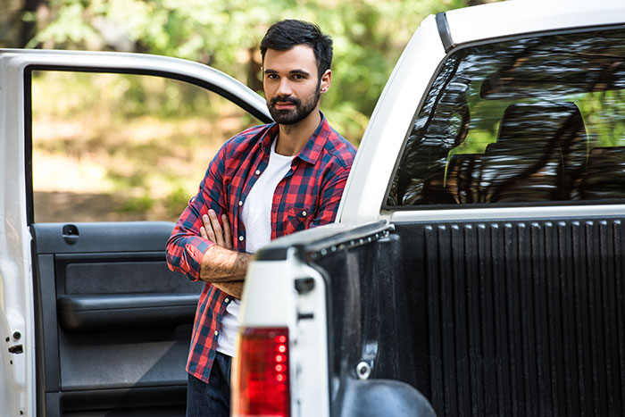 Man standing by open truck door, wearing a plaid shirt, representing manly purchase and advice on responsible decisions.